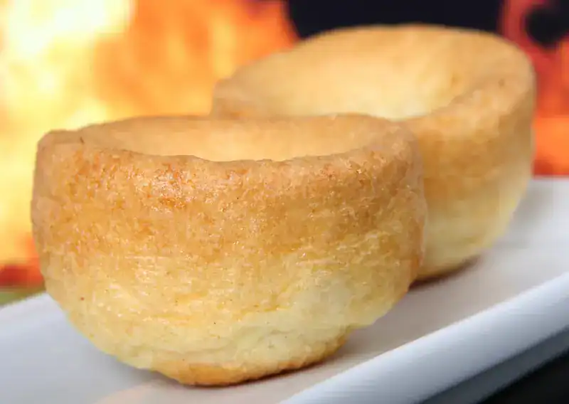 Two golden individual Yorkshire Puddings on a white plate
