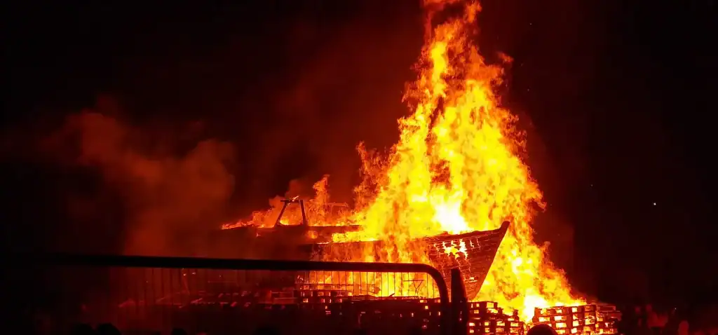 A huge bonfire, featuring a wooden boat at the heart of towering flames