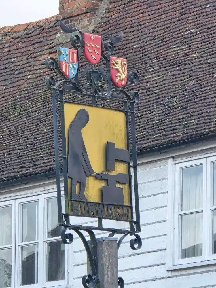 The sign for Burwash which features a blacksmith, a reference to the role Burwash played in the iron industry of the area