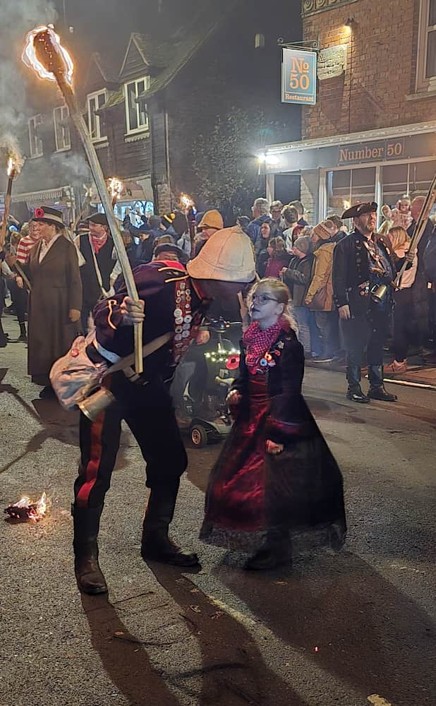 A photo of a member of the procession dressed as a fireman talking to a young girl